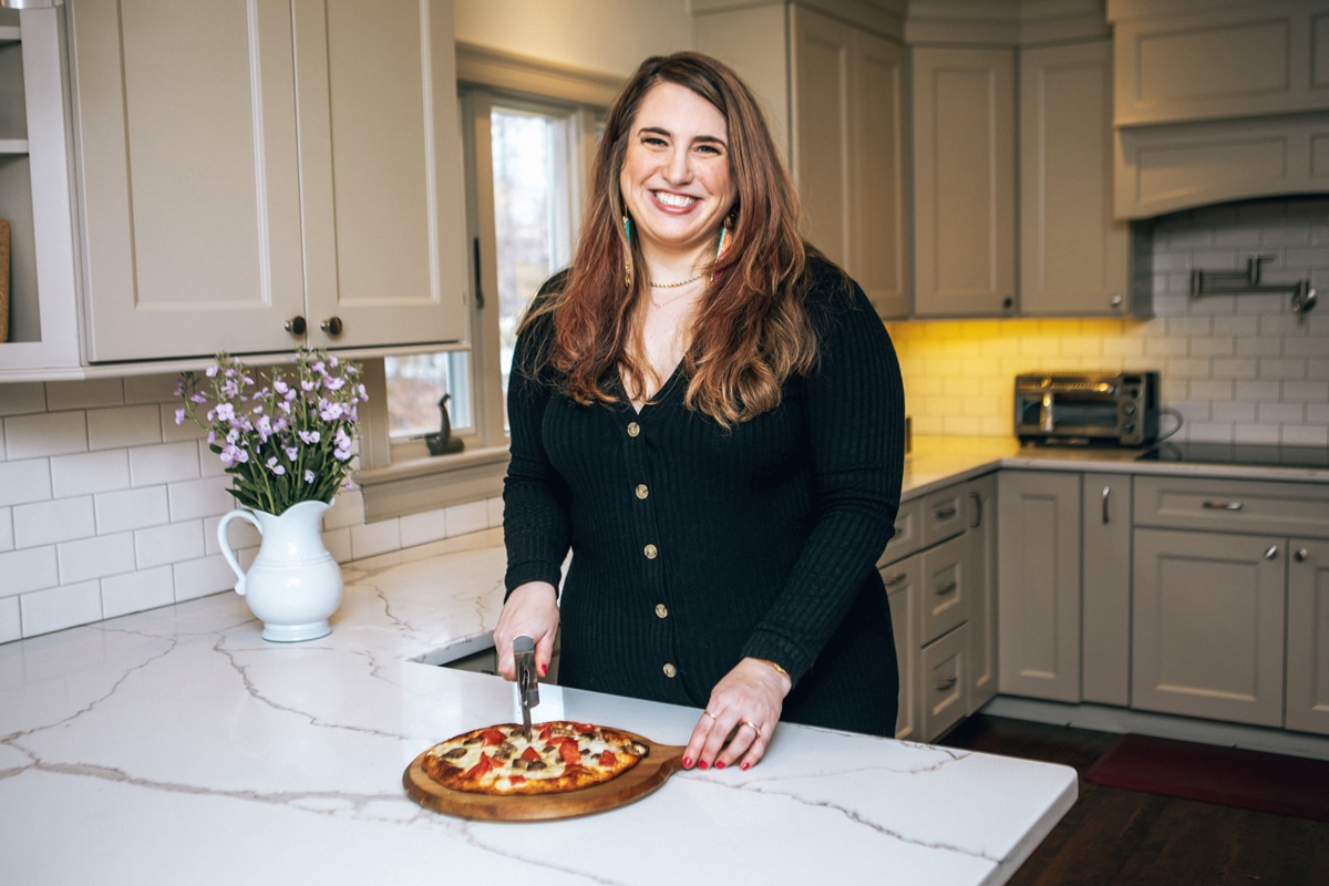 Amy Gorin, lead instructor of Master the Media, cutting a pizza in her kitchen.